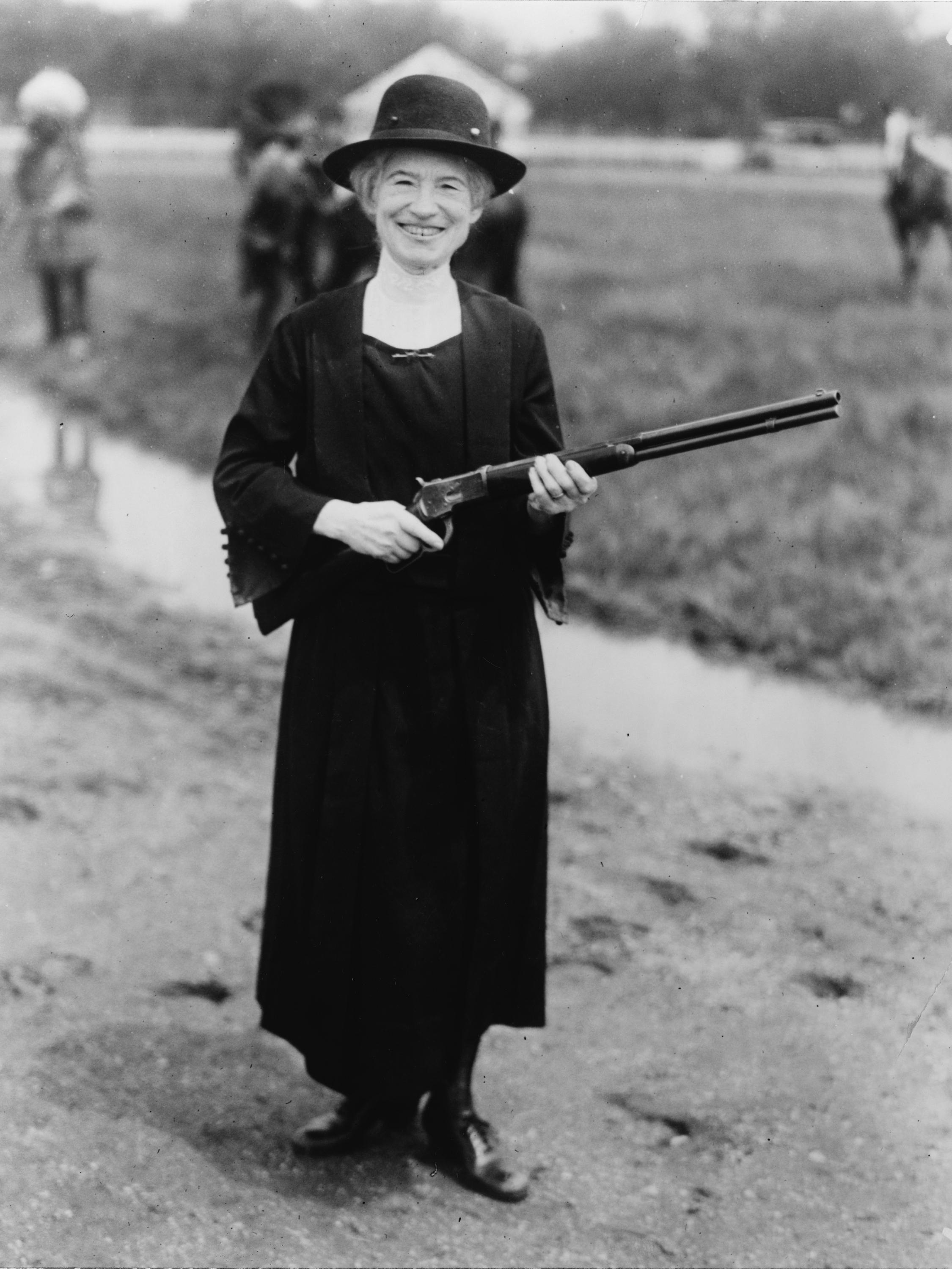 Annie Oakley standing with a double-barrel shotgun