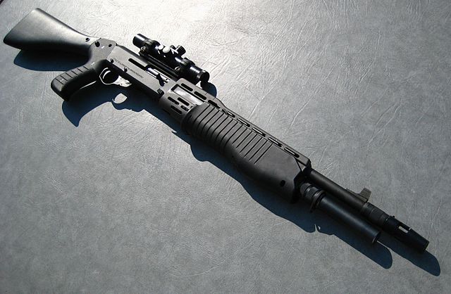 Several guns in a gun case. Two rifles, a pistol, and a shotgun.