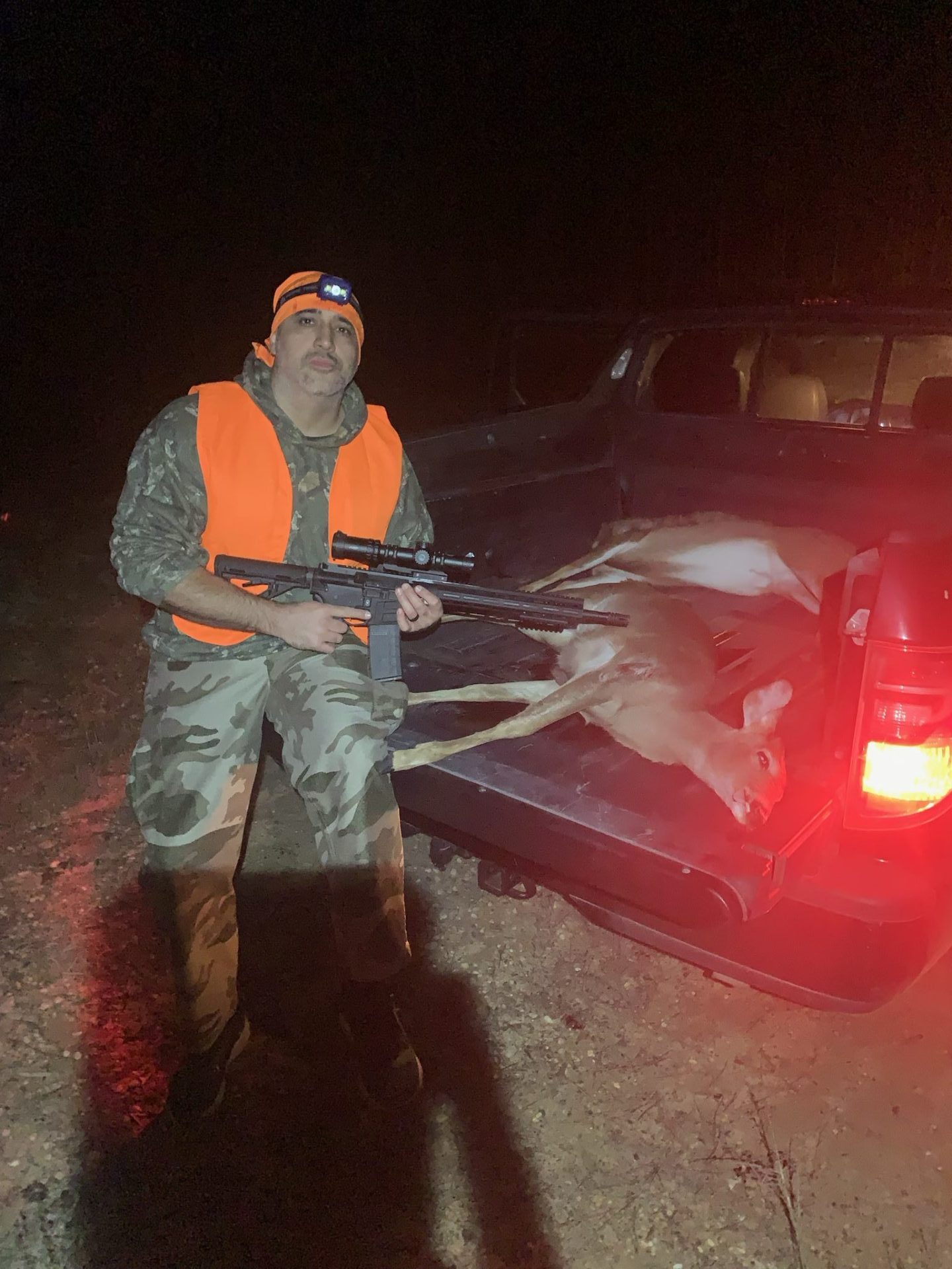 Paris Vega posing with rifle mounted with primary arms lpvo scope next deer that he harvested on a hunt