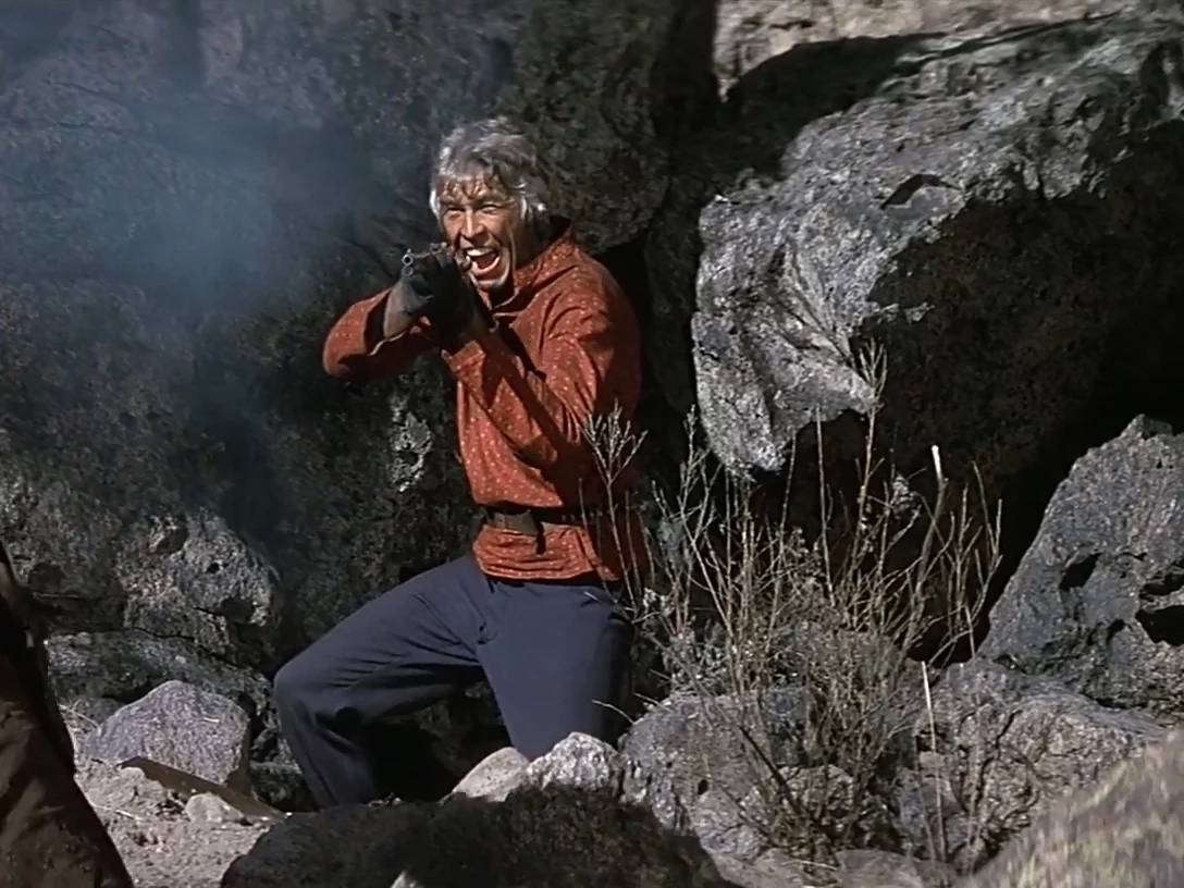 Charlton Heston as Sam Burgade aiming two Colt New Service revolvers in the final gunfight from The Last Hard Men